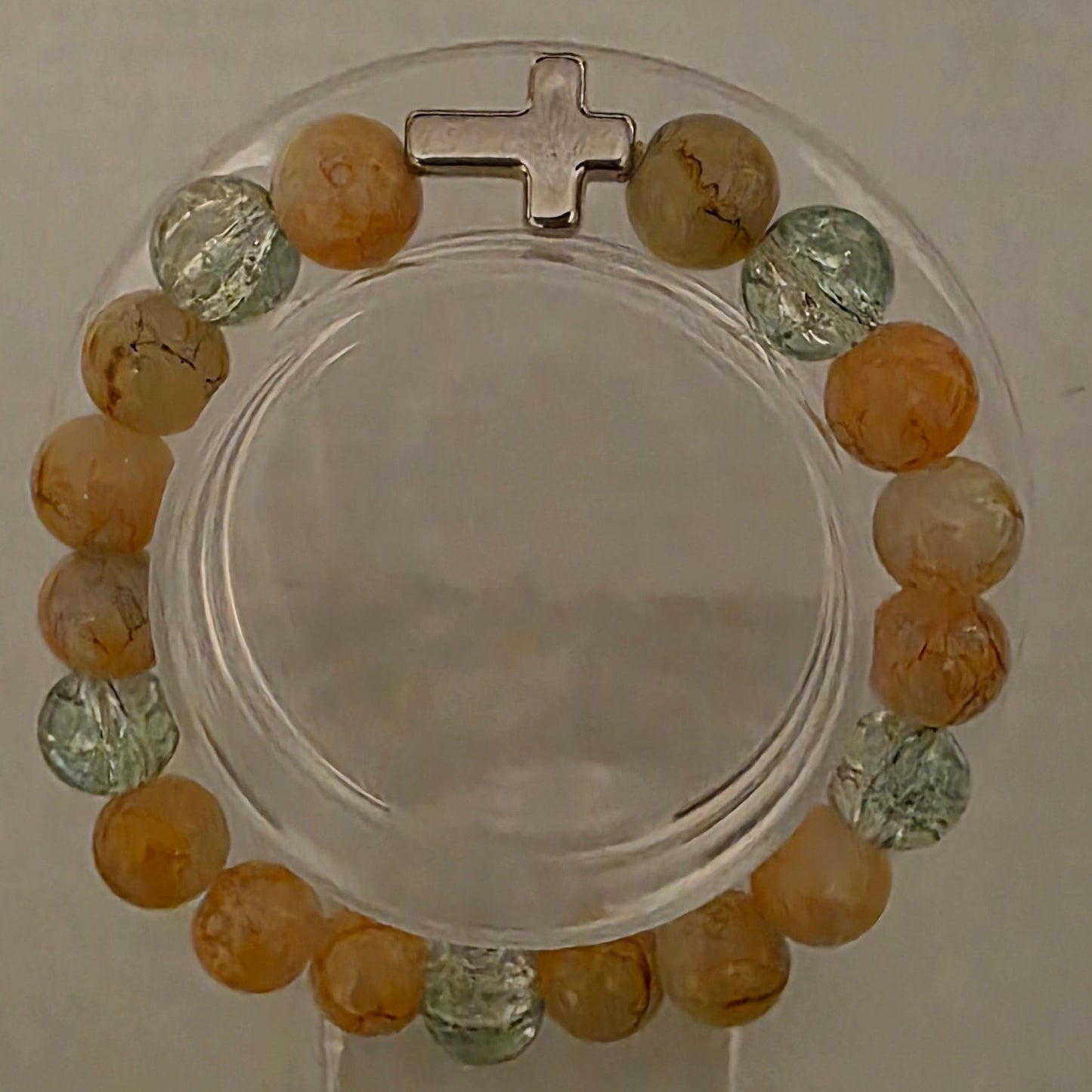Bracelet with multicolored beads and a cross on a beige background
