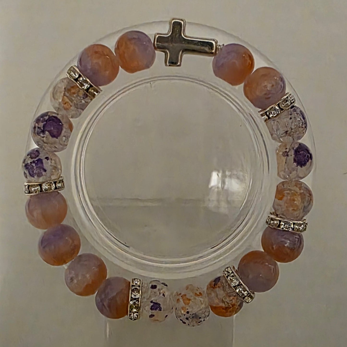 Multicolored beaded bracelet with a cross charm on a white background