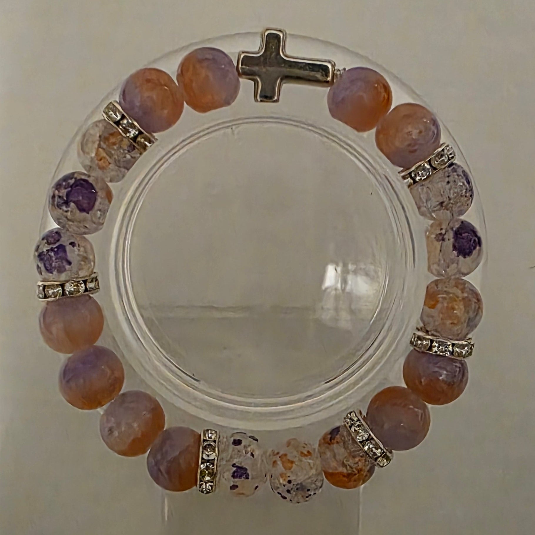 Multicolored beaded bracelet with a cross charm on a white background