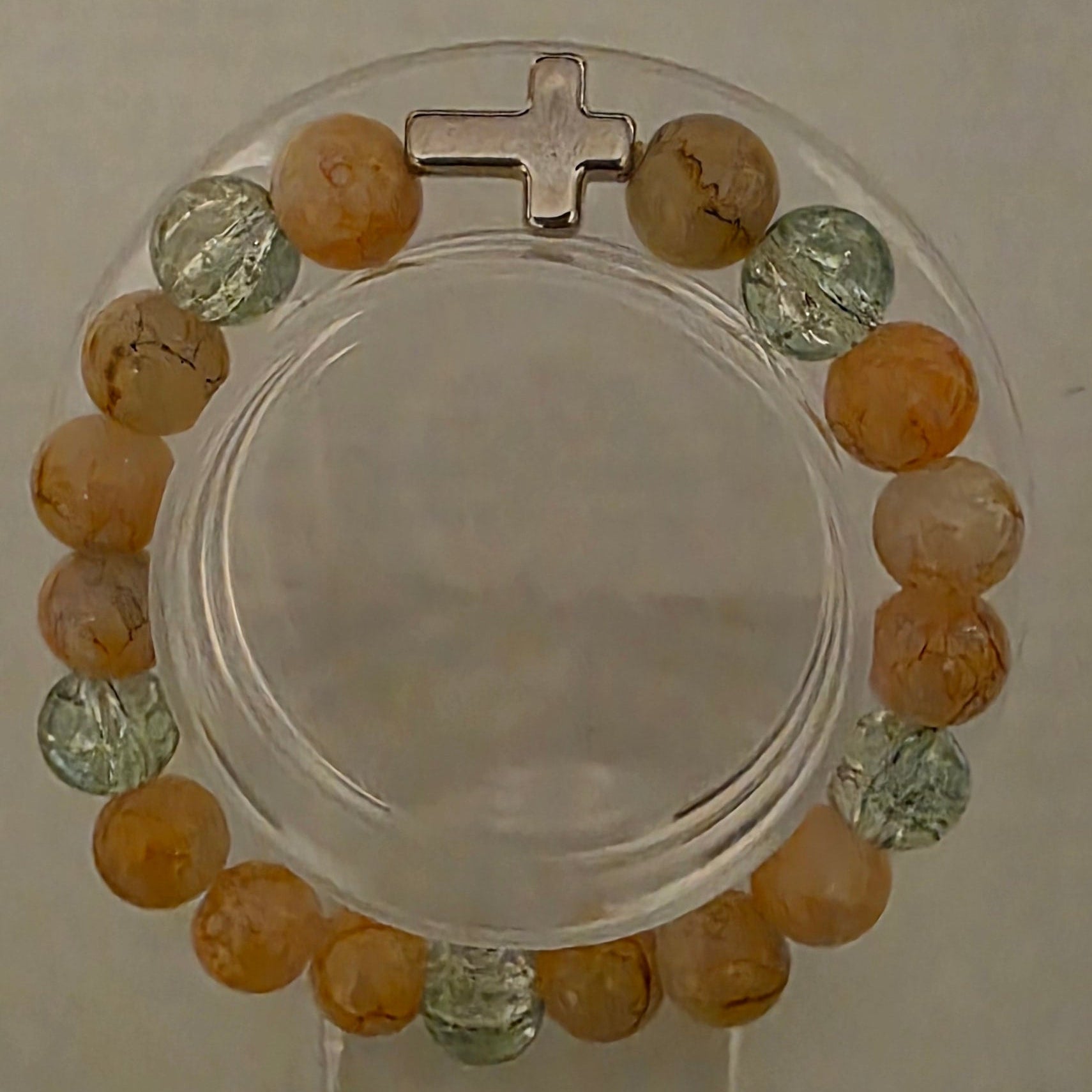 Bracelet with multicolored beads and a cross on a beige background